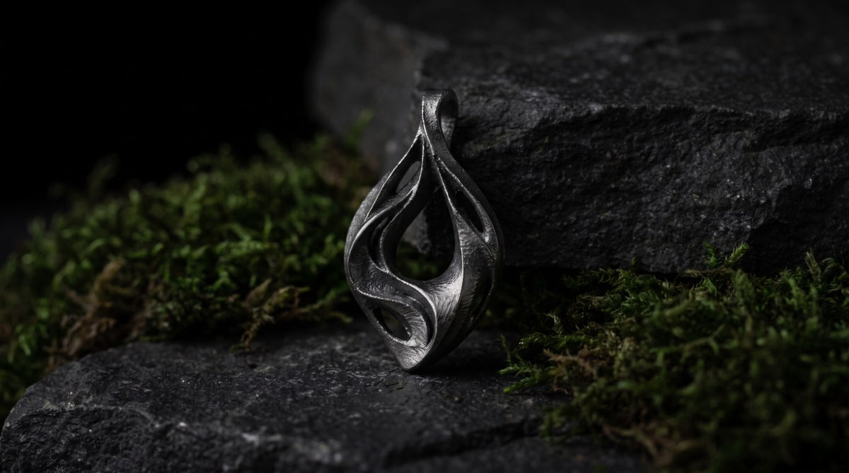Illustrative UNDA pendant on dark river stone beside moss
